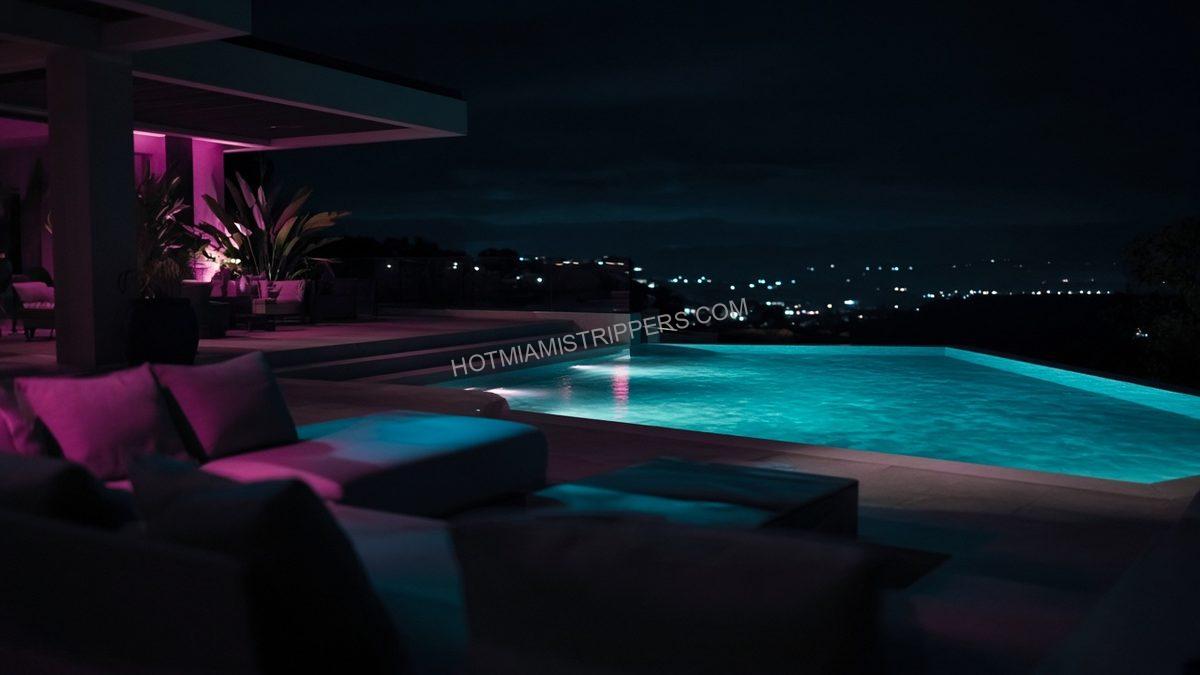 empty villa terrace at night with lounge furniture and pool light