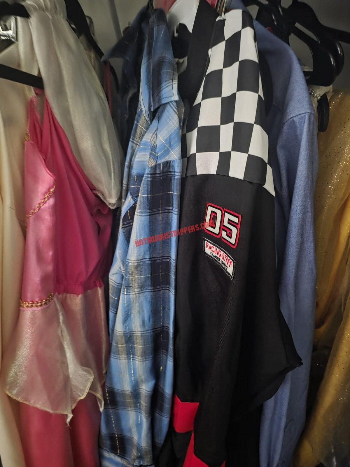 Rack of party costumes including a racing jacket and dresses.