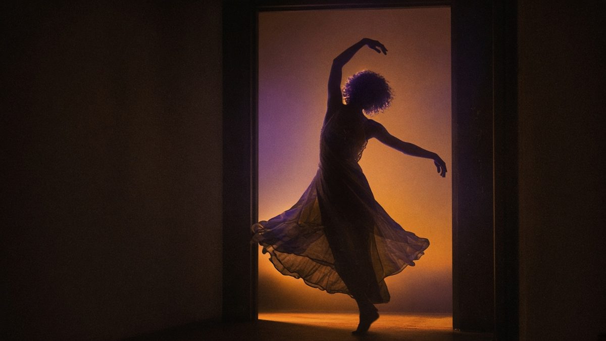 Silhouette of a costumed dancer in a doorway.