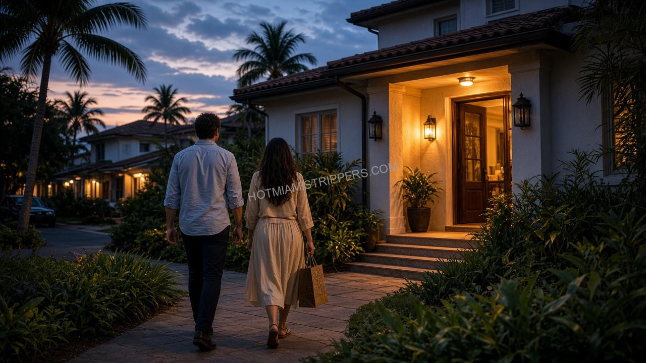 A couple walking up the path to a Miami house at dusk carrying a gift bag